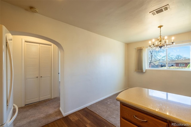 971 Elm Pl, Thornton, CO 80229 - dining area featuring a chandelier, dark wood-style flooring, arched walkways, and baseboards