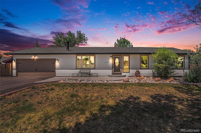 ranch-style house featuring a garage and a lawn