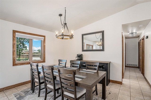 tiled dining room featuring a notable chandelier and lofted ceiling