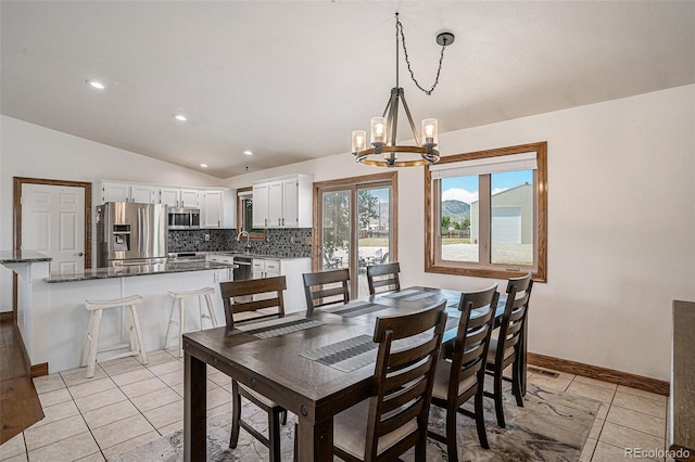 dining area with sink, lofted ceiling, a notable chandelier, and light tile patterned floors