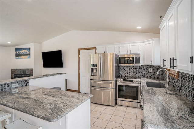 kitchen with decorative backsplash, stainless steel appliances, vaulted ceiling, and sink