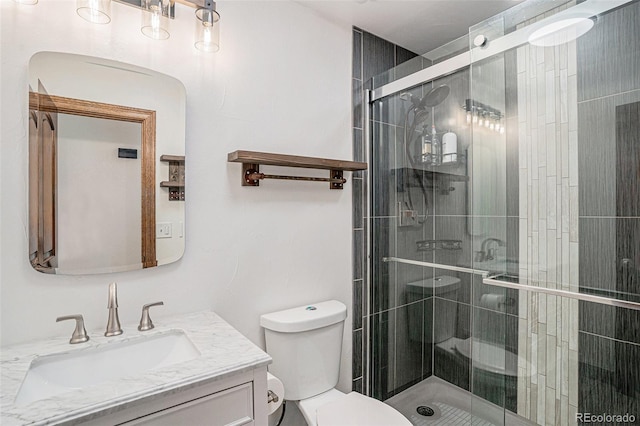 bathroom featuring a shower with shower door, vanity, and toilet