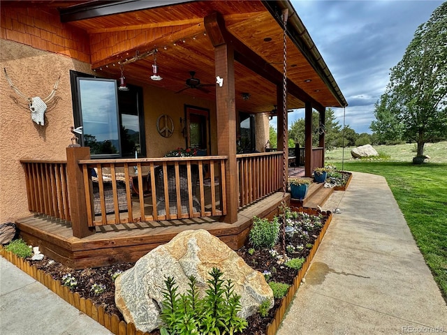 wooden deck featuring a lawn and ceiling fan