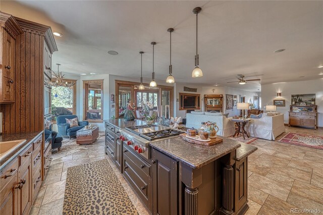 kitchen featuring dark stone counters, ceiling fan, light tile flooring, pendant lighting, and a center island