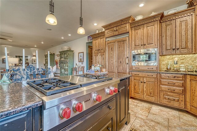 kitchen with dark stone countertops, built in appliances, pendant lighting, tasteful backsplash, and light tile floors