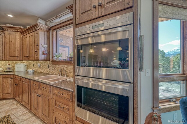 kitchen featuring light tile flooring, sink, stainless steel double oven, and backsplash