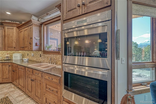 kitchen with double oven, decorative backsplash, and sink