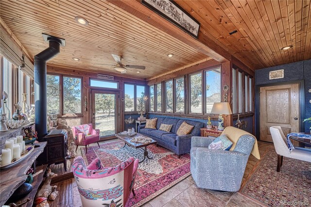 living room with a healthy amount of sunlight, a wood stove, and wooden ceiling