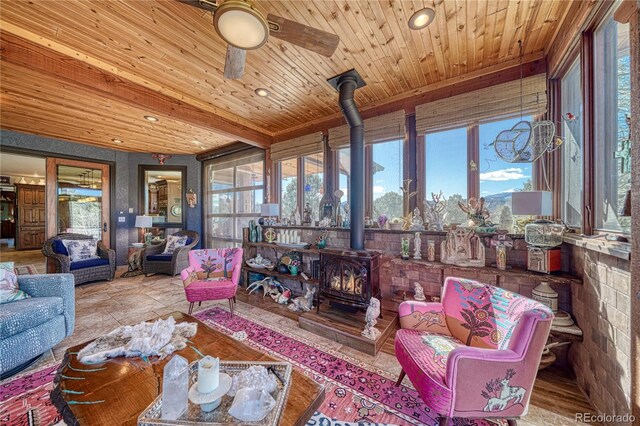 sunroom / solarium featuring wooden ceiling, ceiling fan, and a wood stove