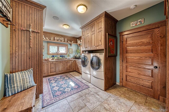 washroom featuring crown molding, washer and clothes dryer, cabinets, and light tile floors