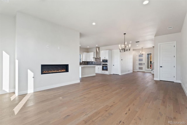 unfurnished living room featuring light hardwood / wood-style flooring and a notable chandelier