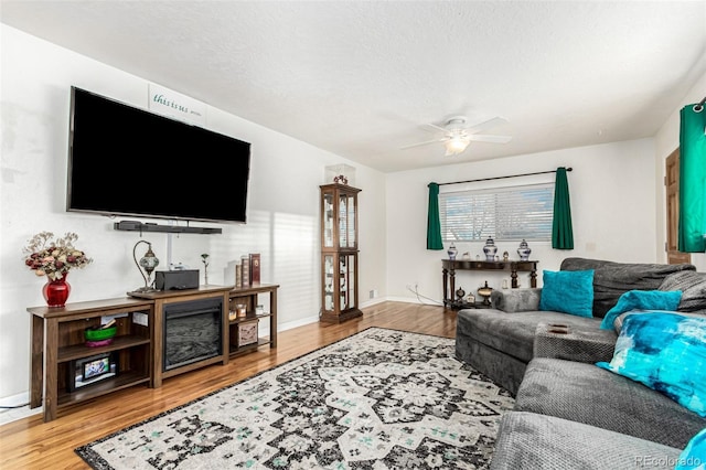 living room with ceiling fan, hardwood / wood-style flooring, and a textured ceiling