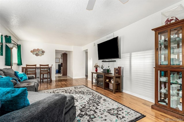 living room featuring hardwood / wood-style flooring, ceiling fan, and a textured ceiling