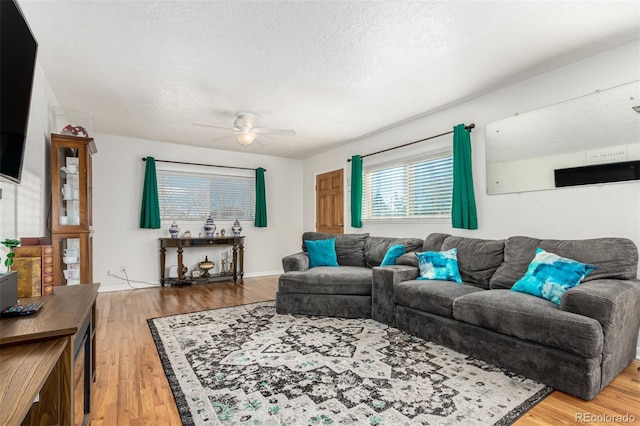 living room with ceiling fan, wood-type flooring, and a textured ceiling