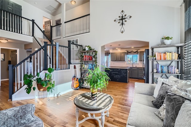 living room featuring a towering ceiling, sink, and light hardwood / wood-style floors