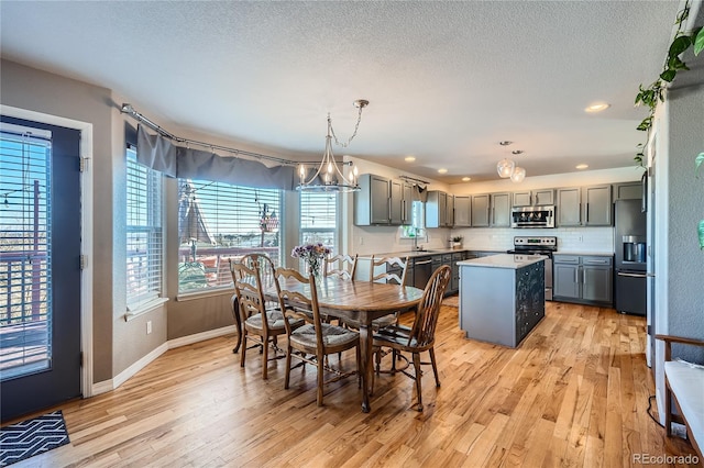 dining area featuring sink, an inviting chandelier, light wood-type flooring, and a textured ceiling