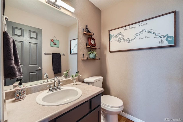 bathroom with toilet, vanity, and hardwood / wood-style flooring