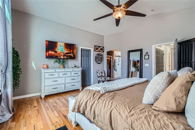 bedroom featuring ceiling fan, a spacious closet, light hardwood / wood-style flooring, and vaulted ceiling