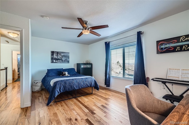 bedroom featuring ceiling fan, hardwood / wood-style floors, and a textured ceiling