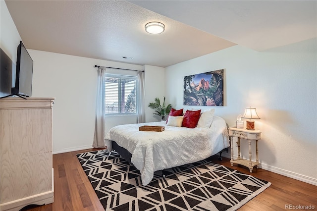 bedroom with a textured ceiling and hardwood / wood-style floors