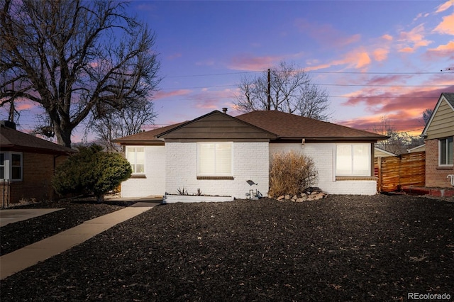 view of front of property featuring fence and brick siding