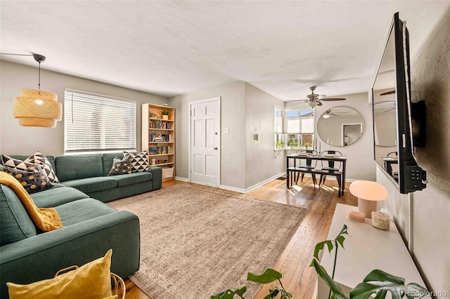 living area with ceiling fan, baseboards, and wood finished floors