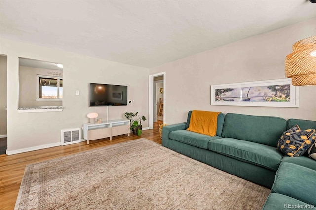 living area featuring wood finished floors, visible vents, and baseboards