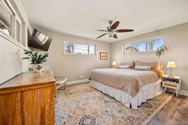 bedroom with a ceiling fan, baseboards, and wood finished floors