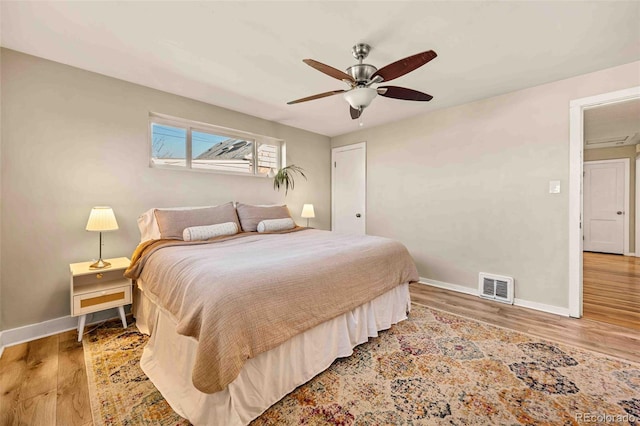 bedroom featuring baseboards, visible vents, ceiling fan, and wood finished floors