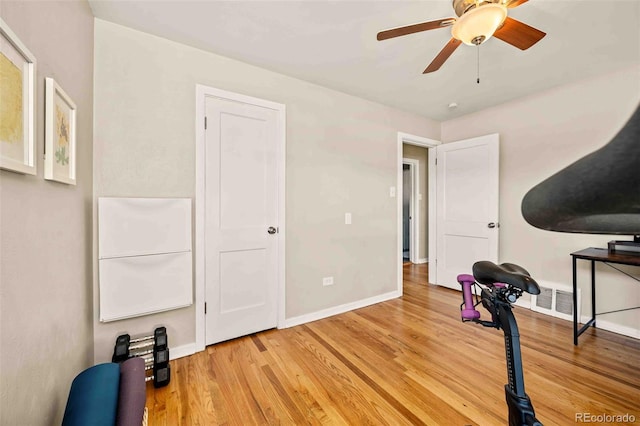 workout room featuring light wood-style floors, visible vents, baseboards, and a ceiling fan