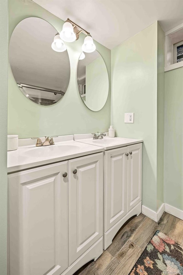 bathroom featuring double vanity, baseboards, a sink, and wood finished floors