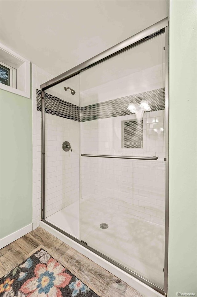 bathroom with a stall shower, baseboards, and wood finished floors