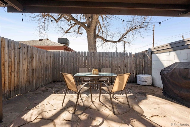 view of patio with outdoor dining space, a fenced backyard, and a grill