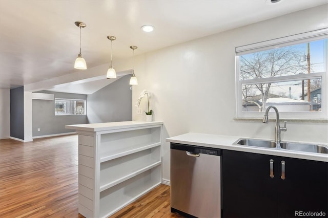 kitchen featuring dishwasher, wood-type flooring, sink, hanging light fixtures, and kitchen peninsula