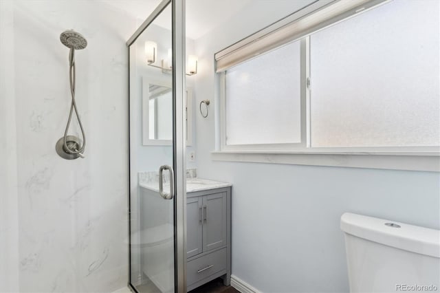 bathroom with toilet, vanity, and a shower with shower door