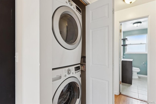 laundry room featuring stacked washer / dryer and light tile patterned floors