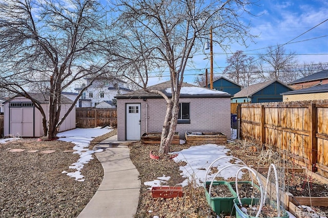 snow covered rear of property with a shed