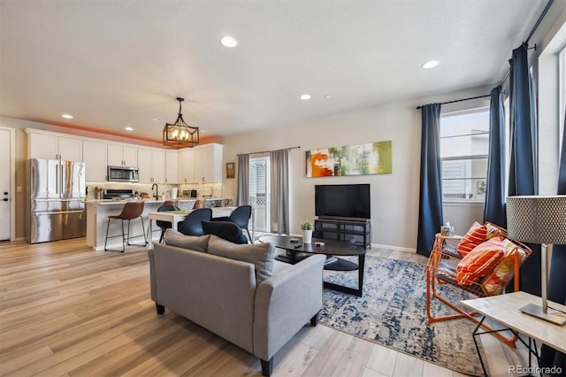 living area featuring light wood-style floors, a chandelier, recessed lighting, and baseboards
