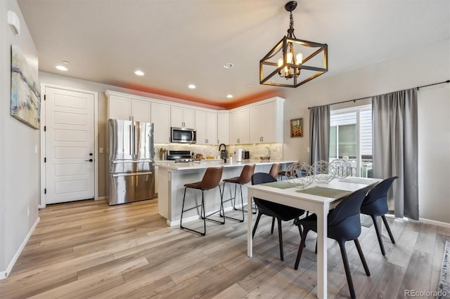 dining space with a chandelier, light wood-style flooring, recessed lighting, and baseboards