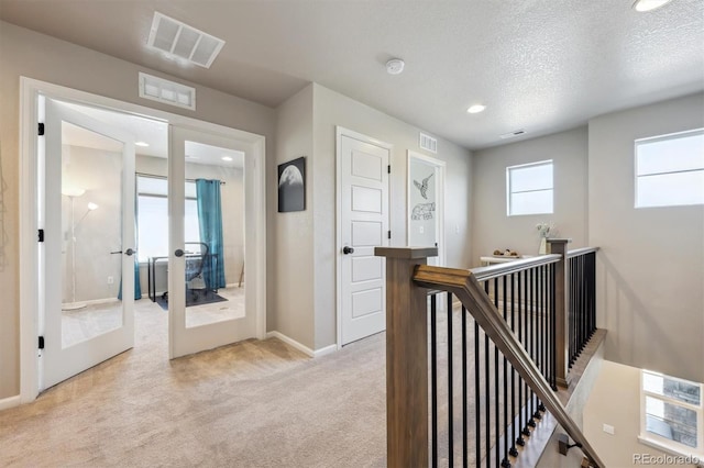 hallway featuring an upstairs landing, light colored carpet, baseboards, french doors, and recessed lighting