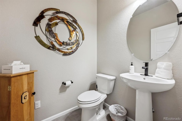 half bath featuring toilet and baseboards