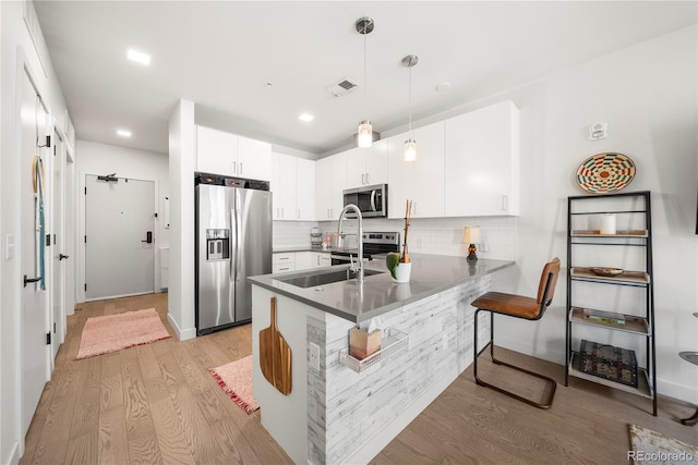 1898 S Bannock St Unit 202, Denver, CO 80223 - kitchen with appliances with stainless steel finishes, light wood-style flooring, tasteful backsplash, a peninsula, and white cabinets