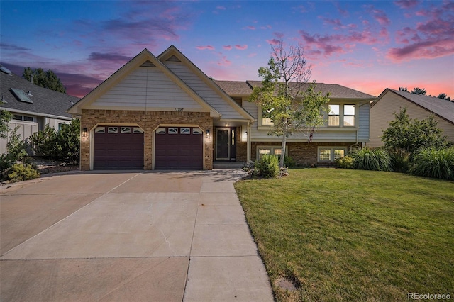 11797 W Aqueduct Dr, Littleton, CO 80127 - view of front facade with concrete driveway, an attached garage, brick siding, and a front lawn