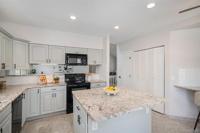11797 W Aqueduct Dr, Littleton, CO 80127 - kitchen with black appliances, light stone counters, a center island, and recessed lighting