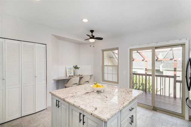 11797 W Aqueduct Dr, Littleton, CO 80127 - kitchen featuring ceiling fan, a center island, light stone counters, recessed lighting, and white cabinets