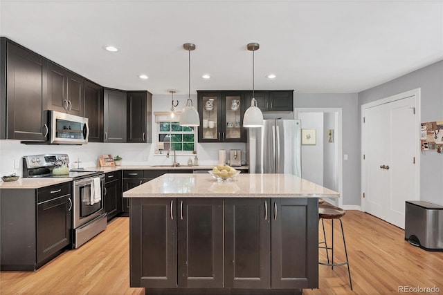 3196 S Newport St, Denver, CO 80224 - kitchen with stainless steel appliances, a center island, a kitchen breakfast bar, light wood-type flooring, and decorative light fixtures