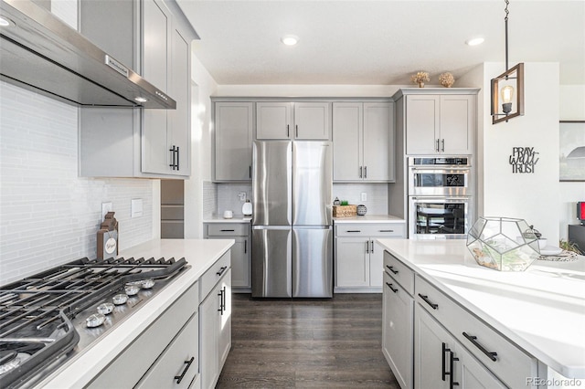 kitchen featuring gray cabinets, hanging light fixtures, wall chimney range hood, and appliances with stainless steel finishes