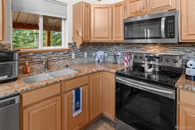 kitchen featuring a sink, stainless steel appliances, light stone counters, decorative backsplash, and light brown cabinets
