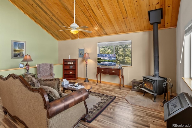 living room with a ceiling fan, vaulted ceiling, wooden ceiling, wood finished floors, and a wood stove
