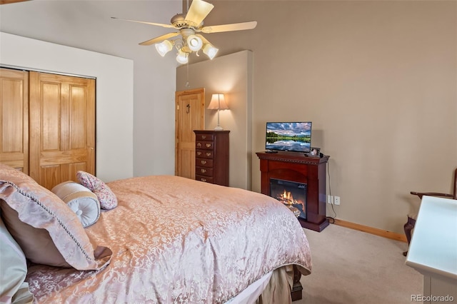 carpeted bedroom with baseboards, ceiling fan, and a glass covered fireplace